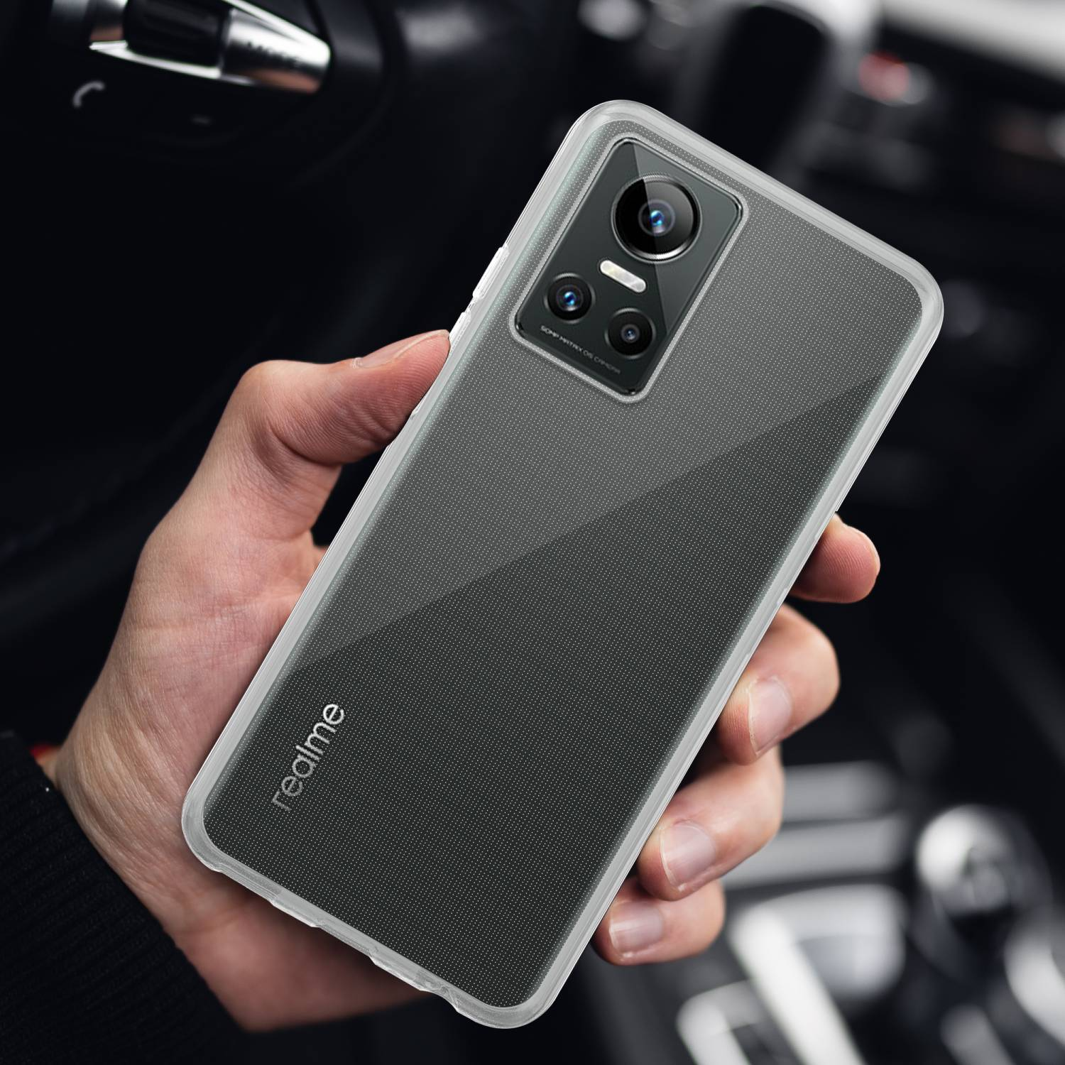 Hand hält ein Telefon mit Hülle. Das Telefon ist schwarz, die Hülle transparent. Realme-Logo auf der Hülle.