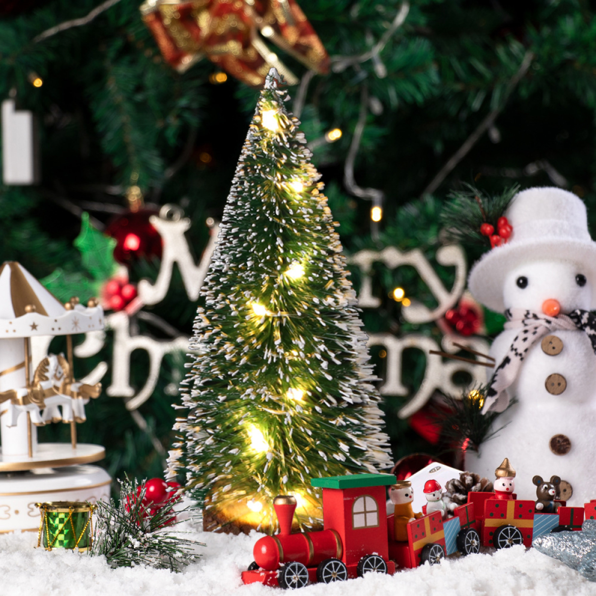 Weihnachtsszene: beleuchteter Weihnachtsbaum, Schneemann, Zug und Geschenke auf Schnee.