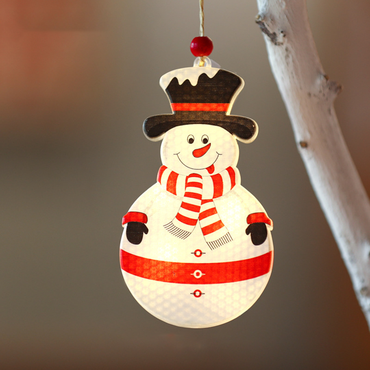 Eine hölzerne Schneemann-Weihnachtsdekoration hängt. Mit rotem Schal, schwarzem Hut, lächelnd.