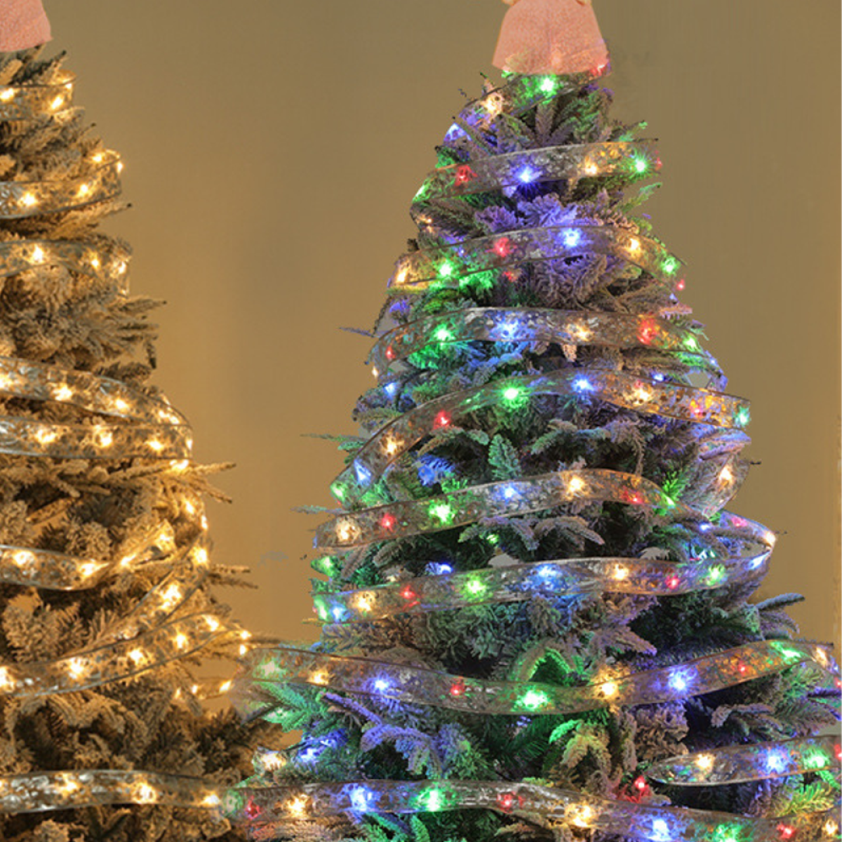 Zwei beleuchtete Weihnachtsbäume. Einer ist mit Lichtern und Schleife umwickelt.
