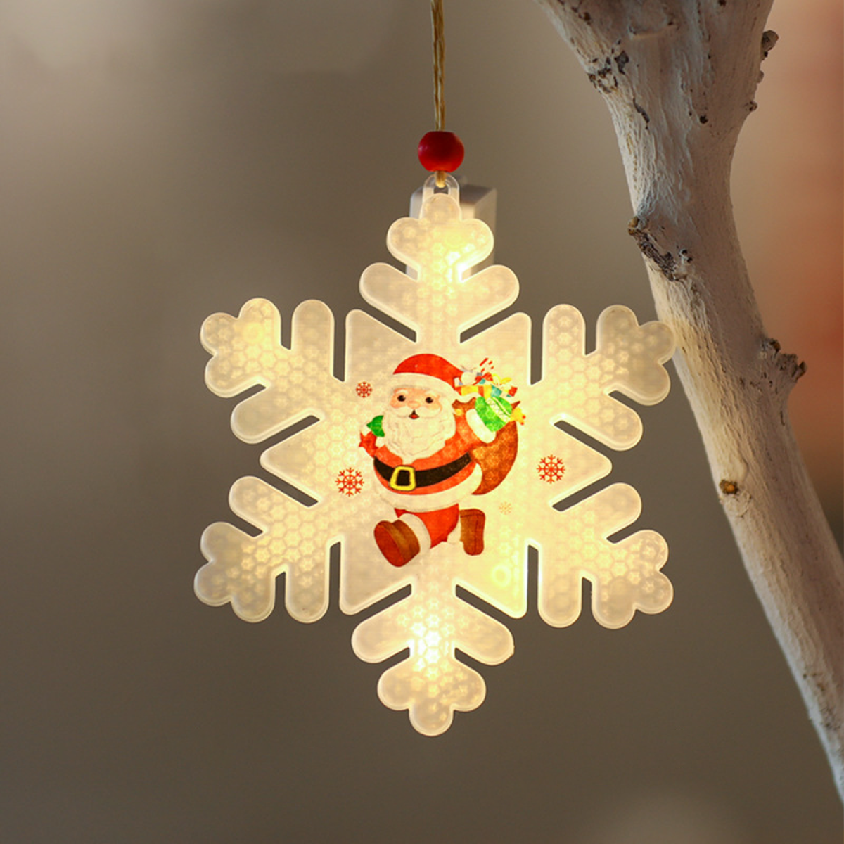 Ein Schneeflocken-Ornament mit Weihnachtsmann hängt. Es leuchtet mit Lichtern.
