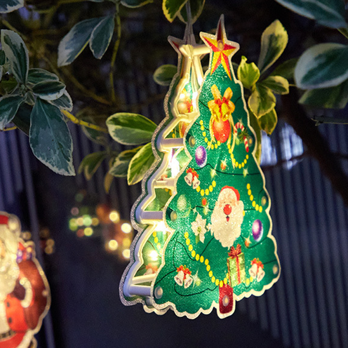 Weihnachtsbaumschmuck, der an einem Baum hängt. Lichter und Ornamente sind sichtbar.