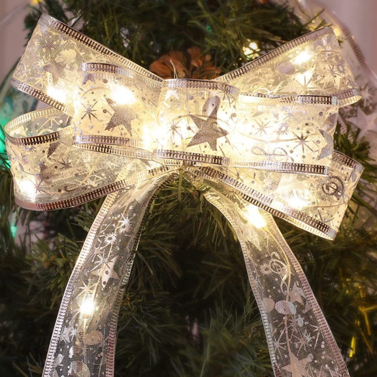 Eine Weihnachtsbaumschleife mit Lichtern. Silber und Weiß mit Sternenmustern.