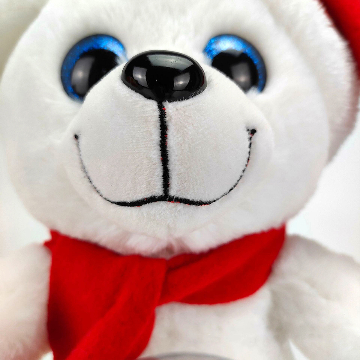 Ein ausgestopfter weißer Teddybär mit blauen Augen, einer schwarzen Nase und einem roten Schal. Weißer Hintergrund.