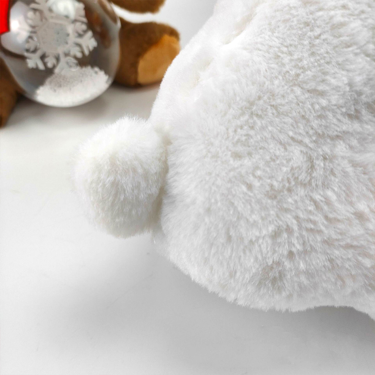 Ein weißes Plüschkaninchen mit einem flauschigen Schwanz, in der Nähe eines Weihnachtsschmucks.
