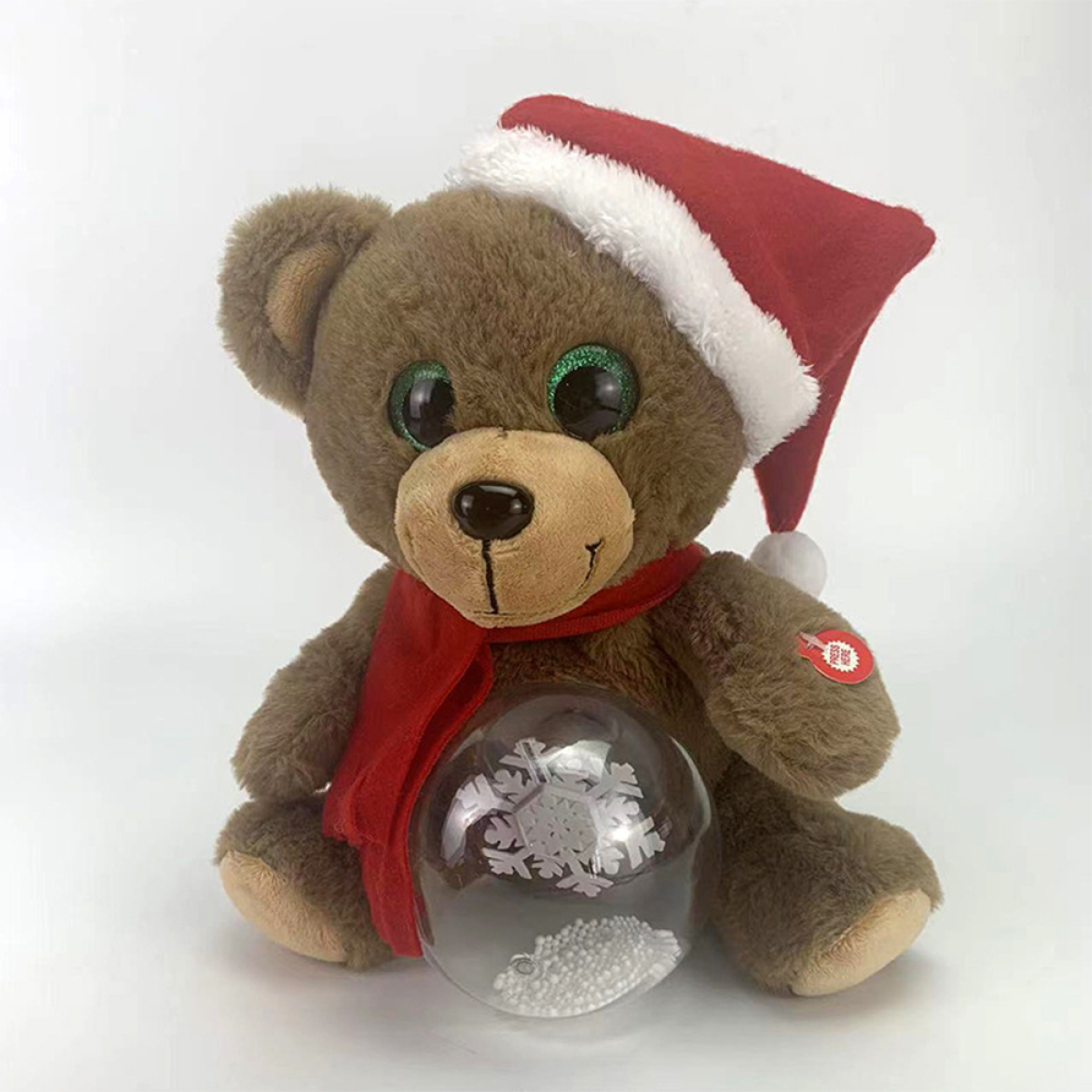 Ein Teddybär mit Weihnachtsmütze und Schal hält eine Schneekugel.