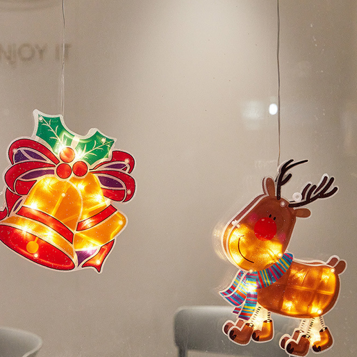 Weihnachtsdekorationen: Leuchtende Rentiere und Glocken hängen. Festliches, warmes Licht.