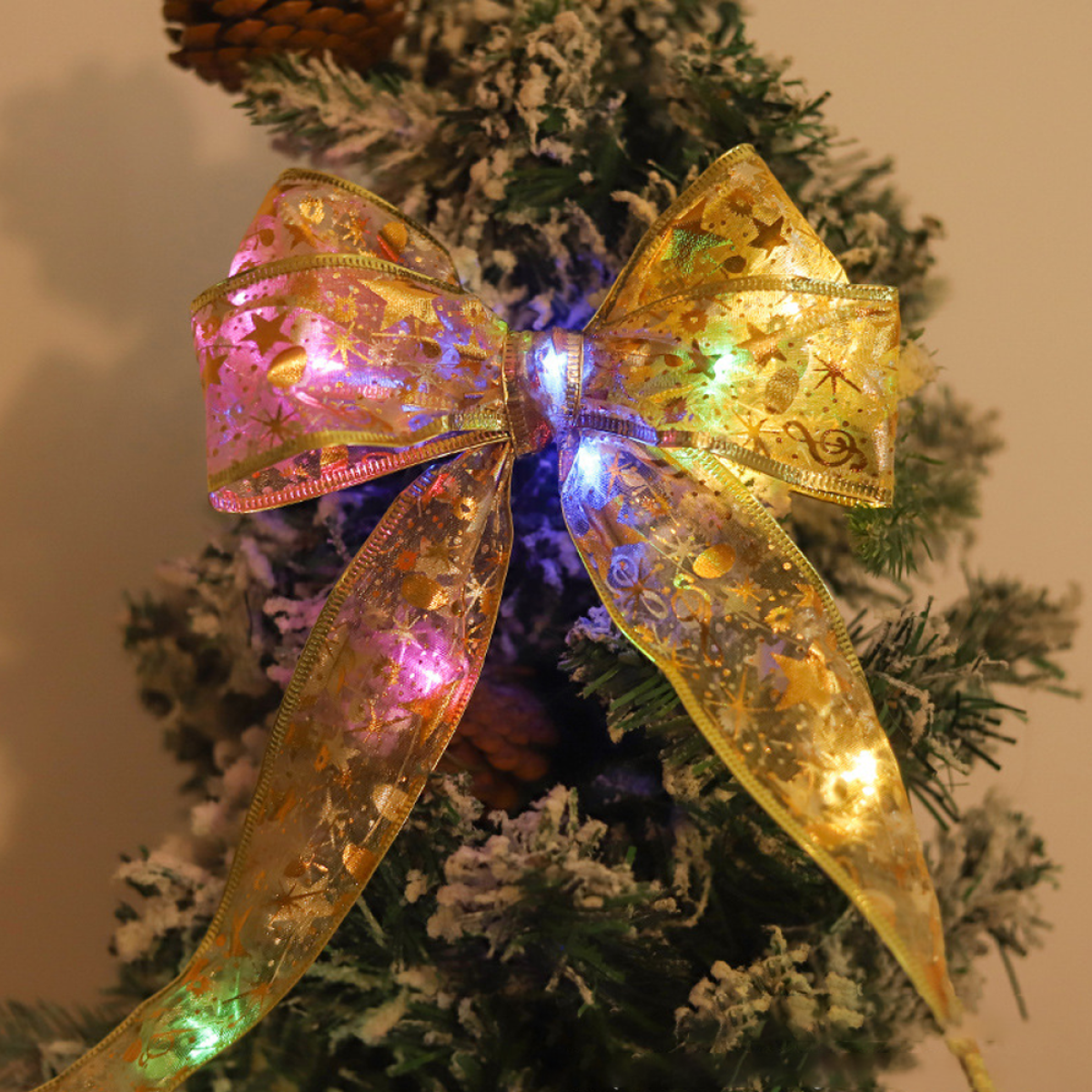 Weihnachtsschleife mit Lichtern. Die Schleife ist goldfarben und hat Sterne. Sie ist auf einem Baum.