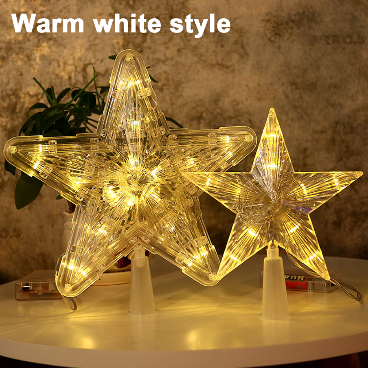 Zwei sternförmige warmweiße Lichter auf einem Tisch, die eine festliche und beleuchtete Atmosphäre schaffen.