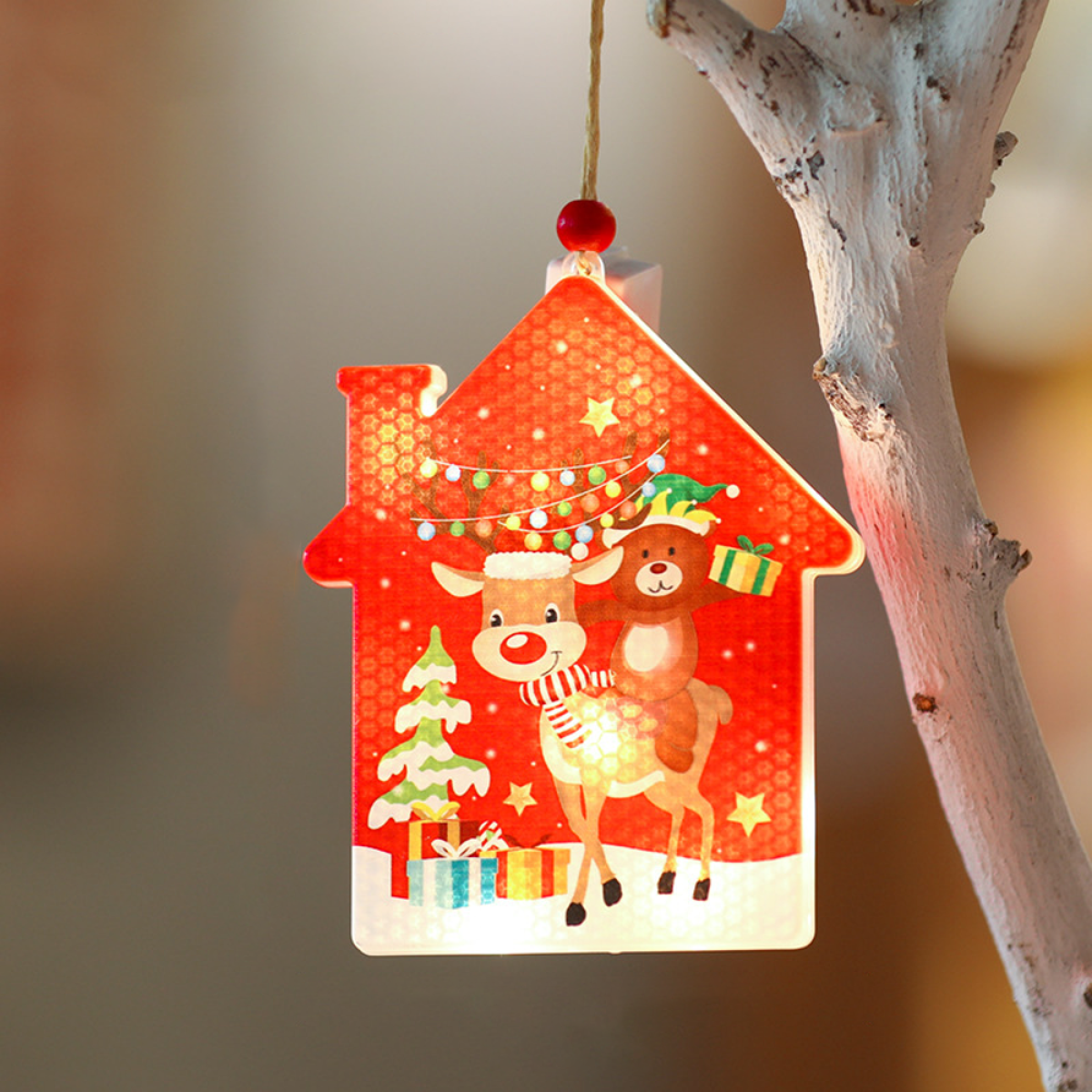 Rotes, hausförmiges Weihnachtslicht. Rentier und Bär reiten zusammen. Grüner Baum und Geschenke. Weißer Hintergrund.