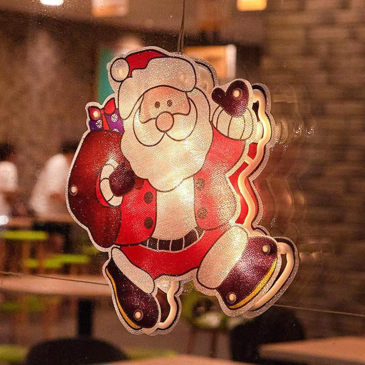 Leuchtende Santa Claus-Dekoration mit rotem Anzug, weißem Bart und schwarzen Stiefeln, hängt vor einem Fenster.
