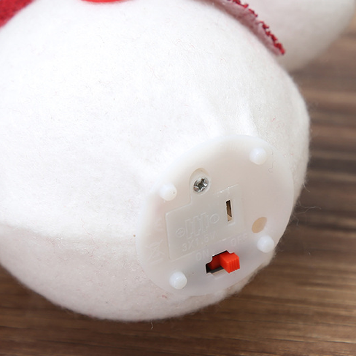 Sockel eines Schneemann-Ornaments mit Ein/Aus-Schalter und Batteriedetails, Nahaufnahme.