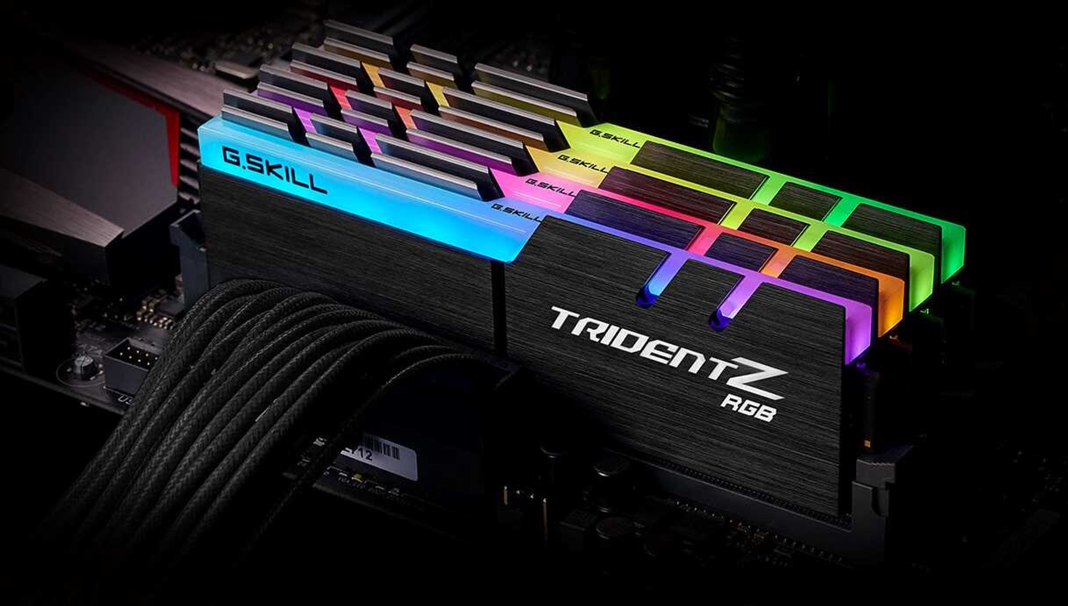 Pamięci RAM RGB zainstalowane na płycie głównej. Pamięć RAM ma logo Trident Z RGB. Czarne tło.