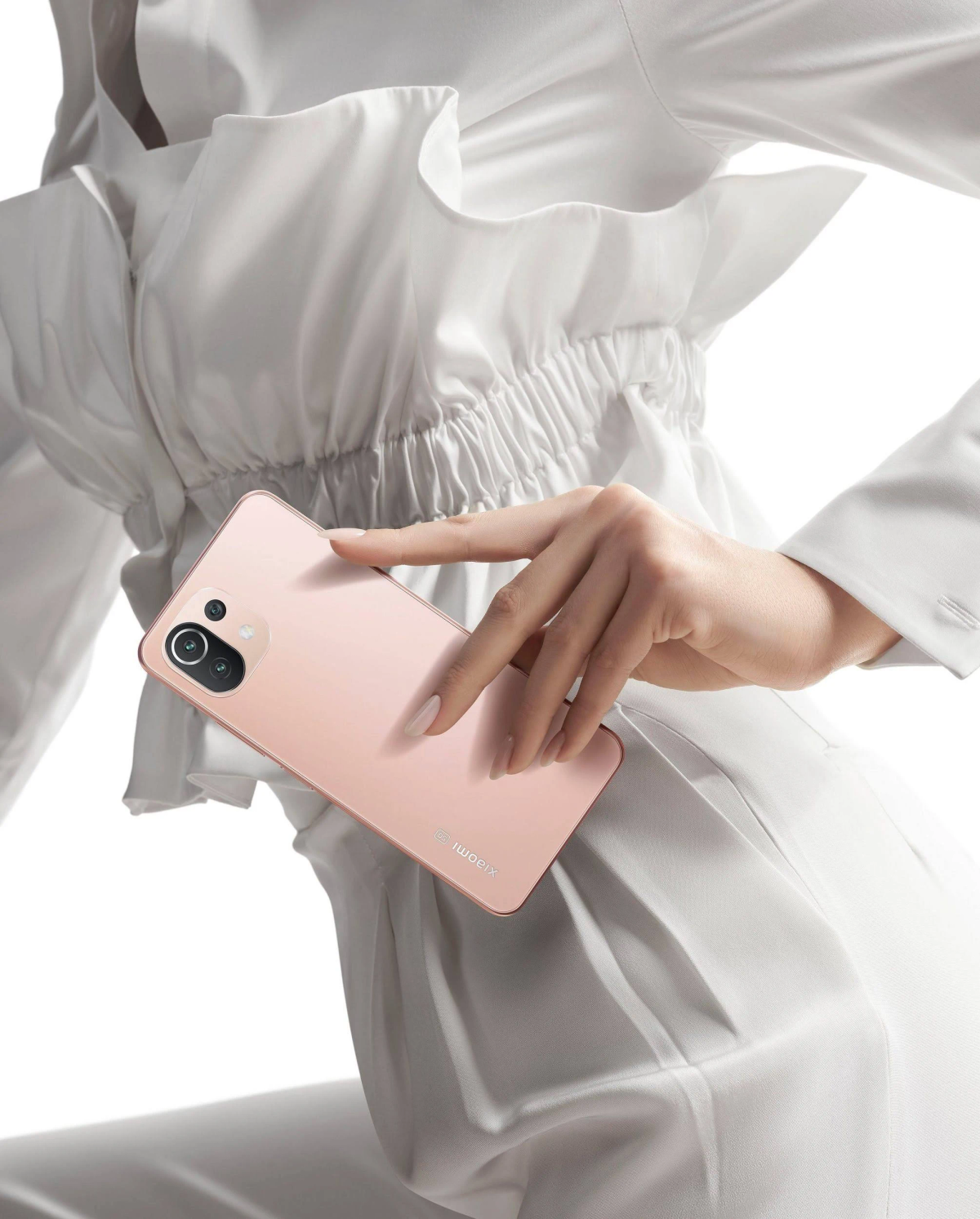 Ręce kobiety trzymającej różowy smartfon. Telefon ma białe logo Xiaomi.