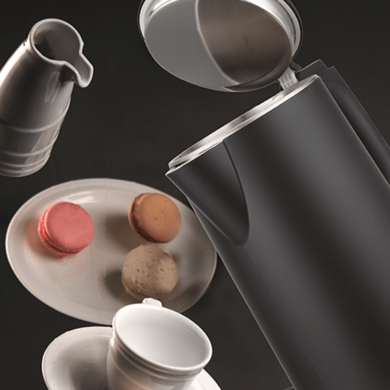 Hervidor negro con tapa abierta, plato con macarons y una taza.