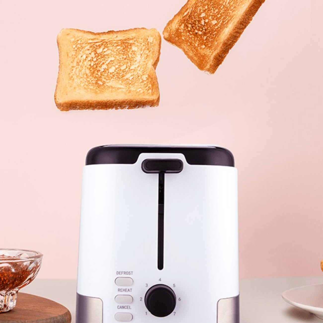 Biały toster z dwoma kawałkami chleba wyskakującymi. Różowe tło. Miska dżemu w rogu.