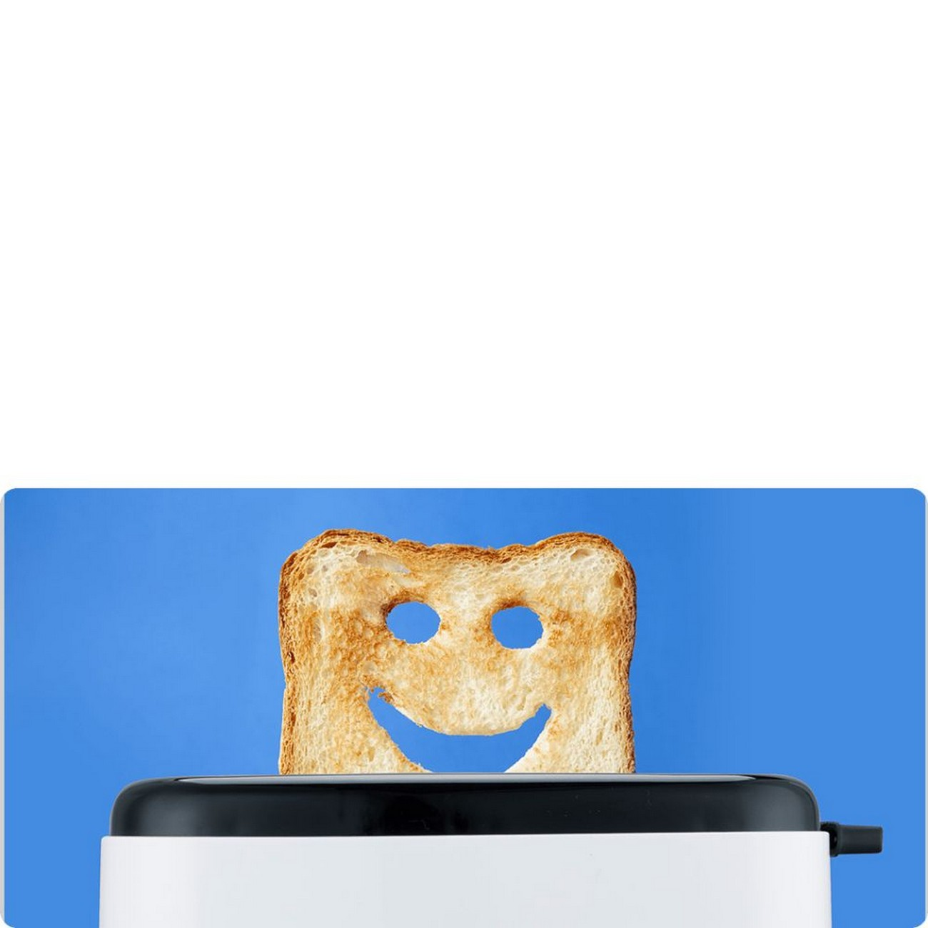 Toster z kromką tostowanego chleba, wycięciem w kształcie uśmiechniętej buzi, na niebieskim tle.