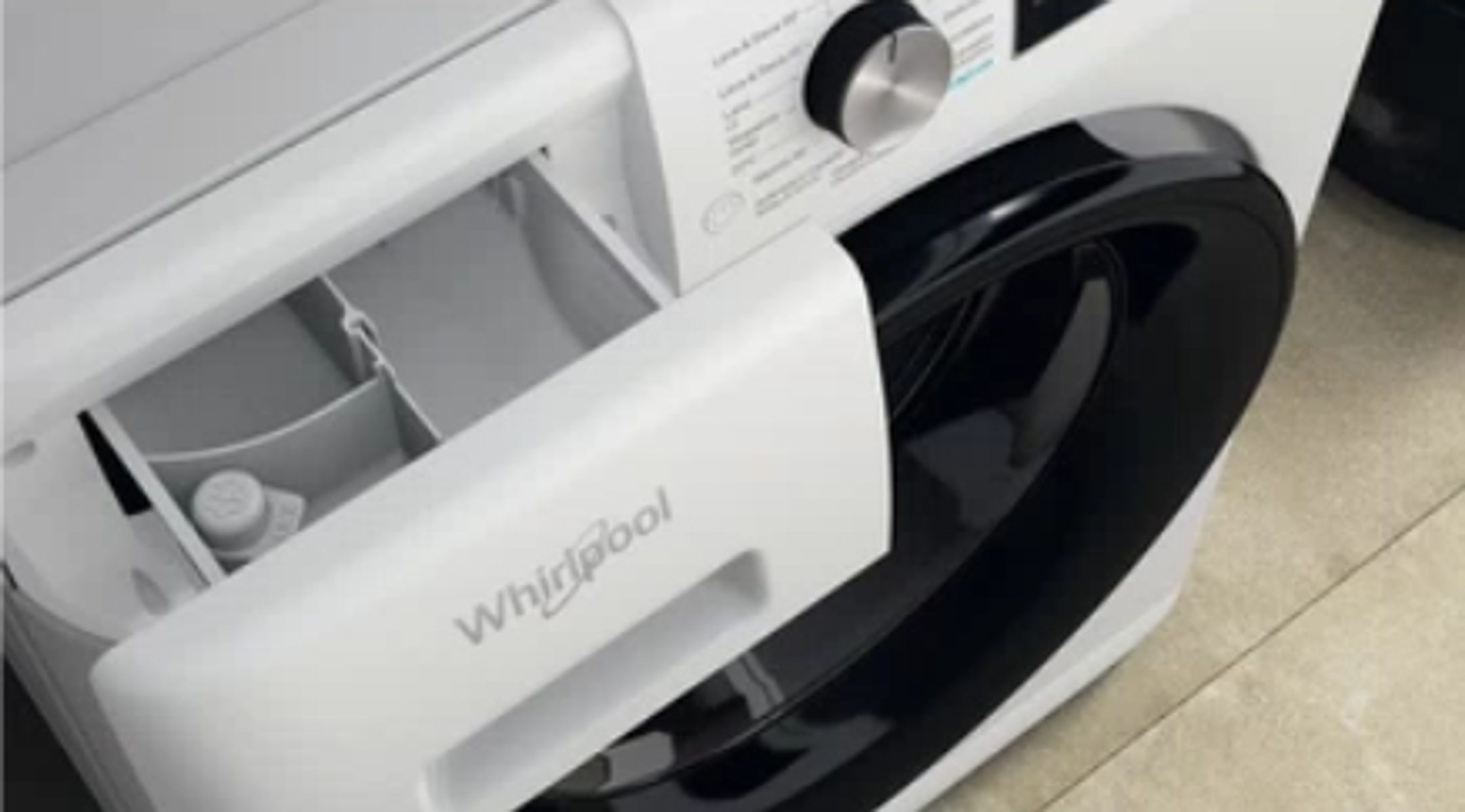 Un cajón blanco de lavadora Whirlpool abierto. Muestra los compartimentos.