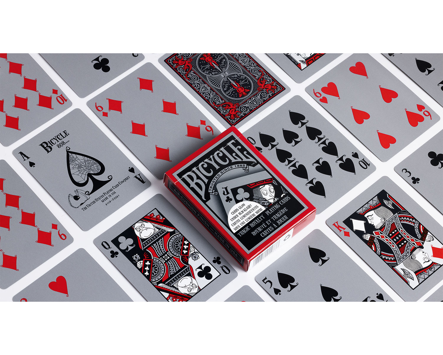 Eine rote und schwarze Bicycle-Spielkartenbox mit Karten auf grauem Hintergrund verstreut.