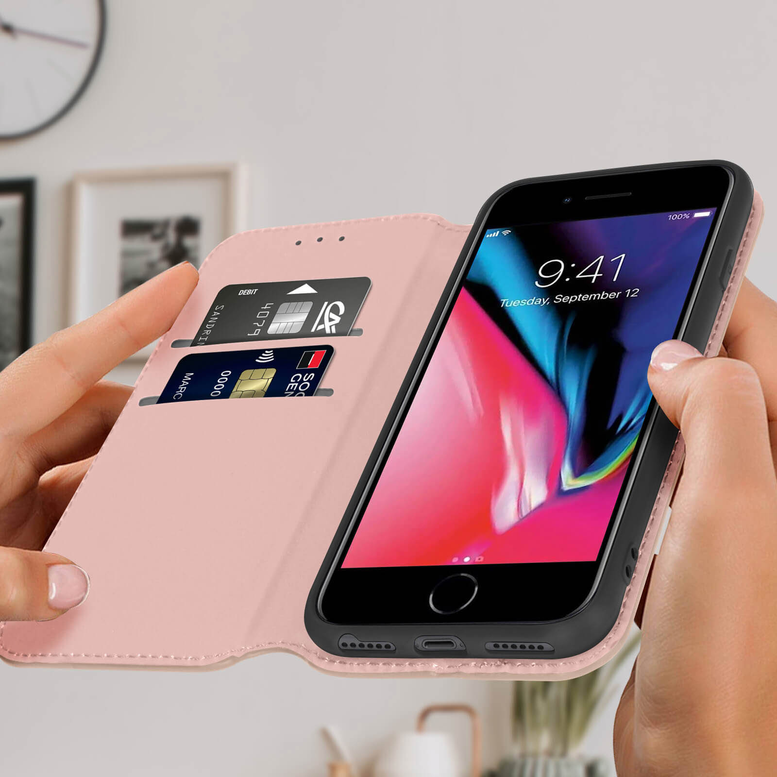 Une main tenant un étui de téléphone rose avec un téléphone, cartes de crédit visibles, sur fond blanc.