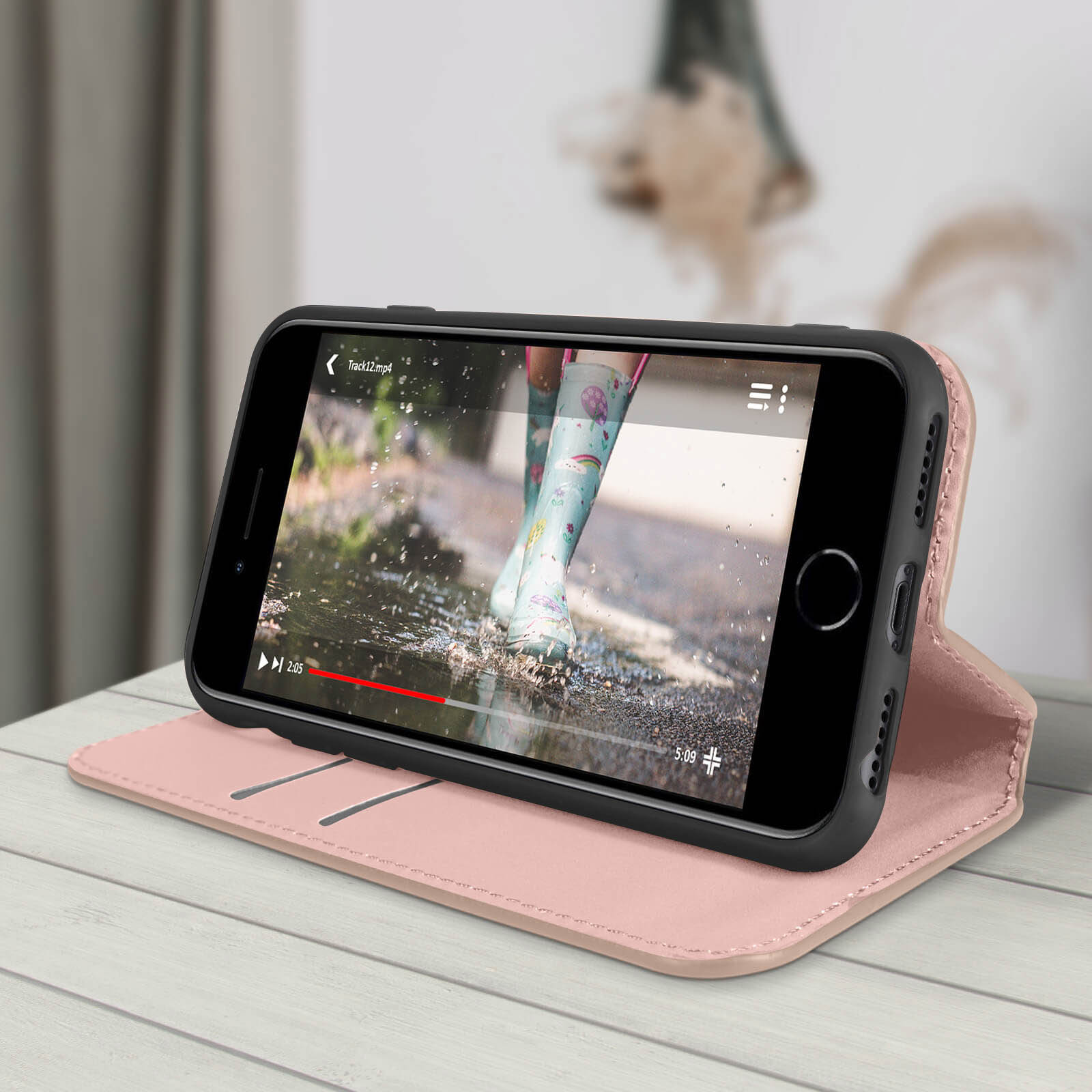 Un téléphone affichant une vidéo sur un étui rose sur une table en bois.