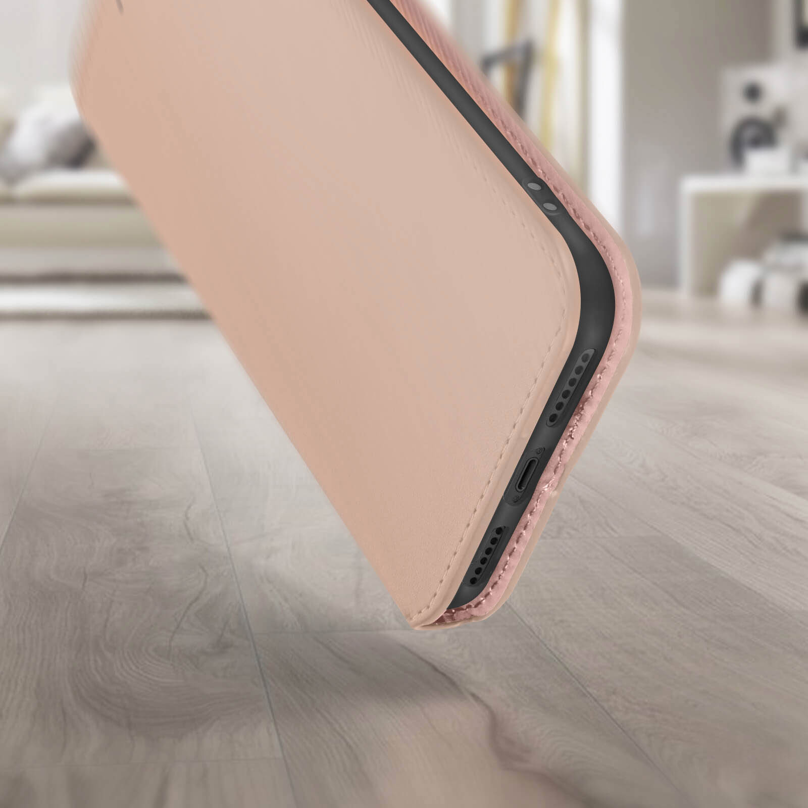 Un étui de téléphone rose, partiellement ouvert, sur un sol en bois. L'arrière-plan est flou.