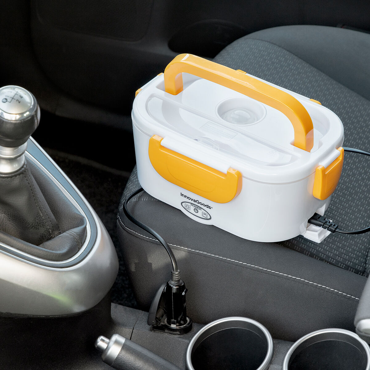 Un portapranzo all'interno di un'auto, collegato a una presa di corrente. Il portapranzo è bianco e arancione.