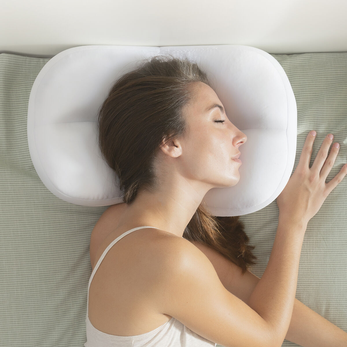 Una donna che dorme su un cuscino bianco, con la testa appoggiata.