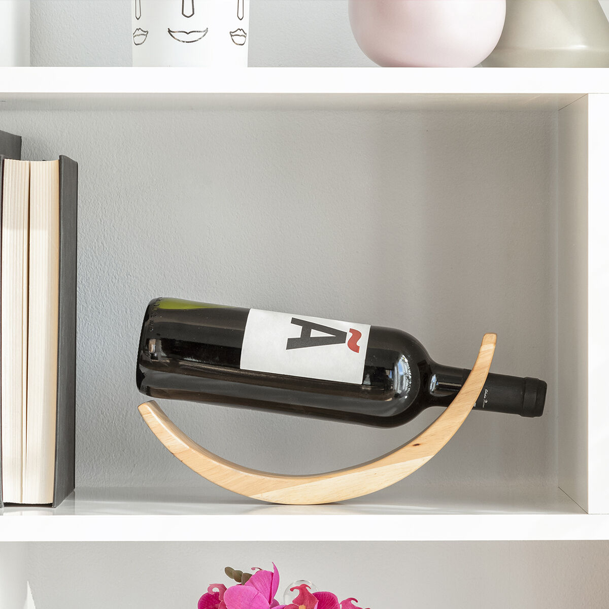 Bottiglia di vino in una culla di legno su uno scaffale. L'etichetta ha la lettera 'A'.