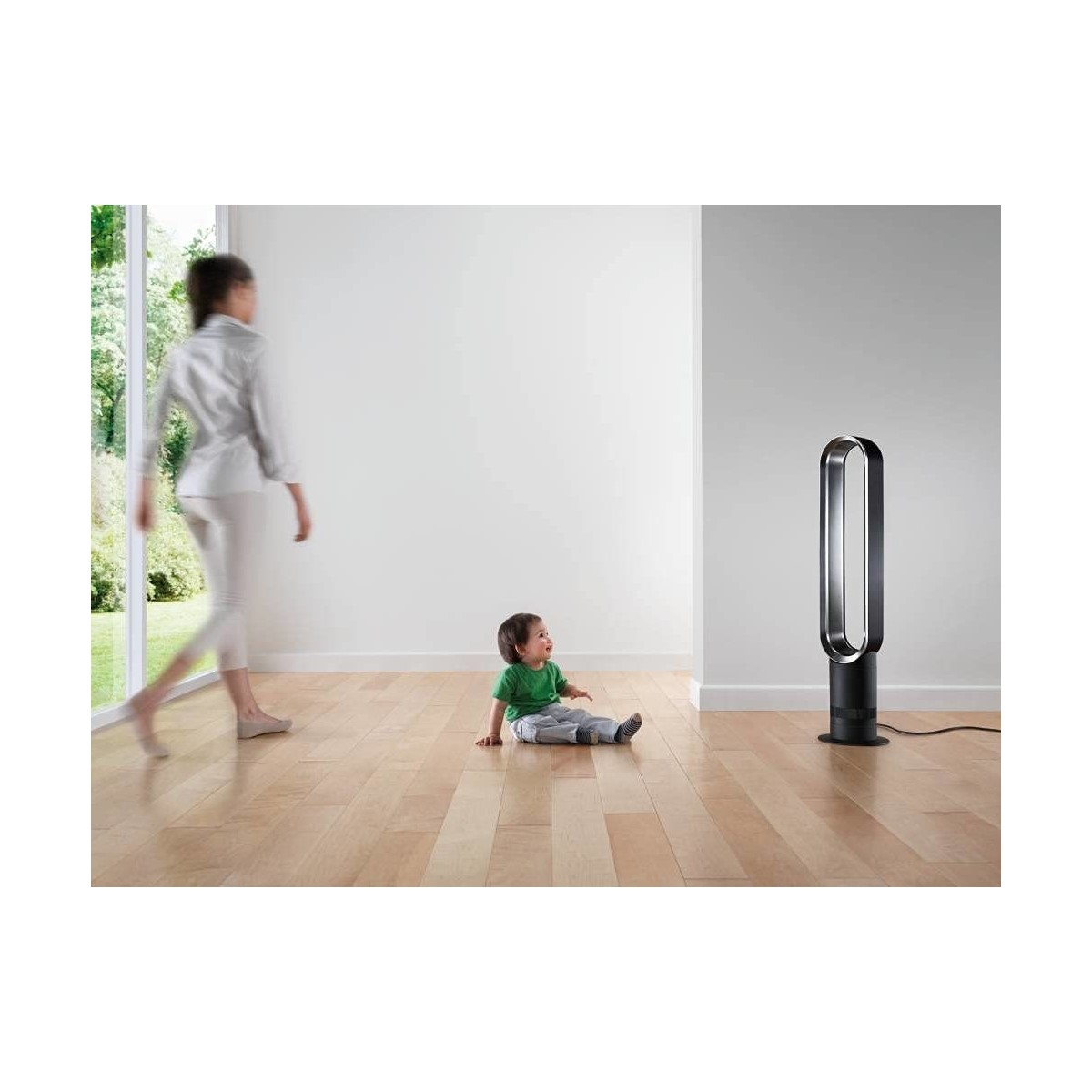 Eine Frau und ein Kind mit einem Ventilator. Das Kind sitzt auf dem Boden und schaut den Ventilator an, die Frau geht.