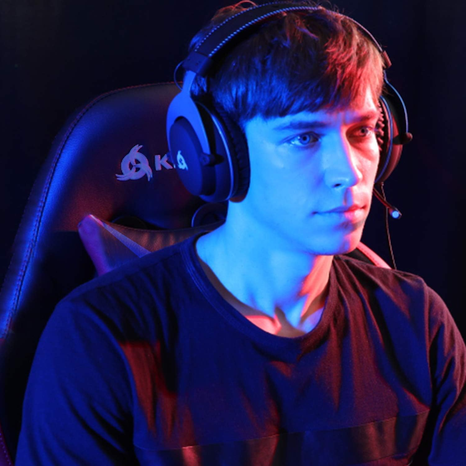 Ein Mann mit Gaming-Headset und Mikrofon, der unter Neonlicht auf den Bildschirm schaut.
