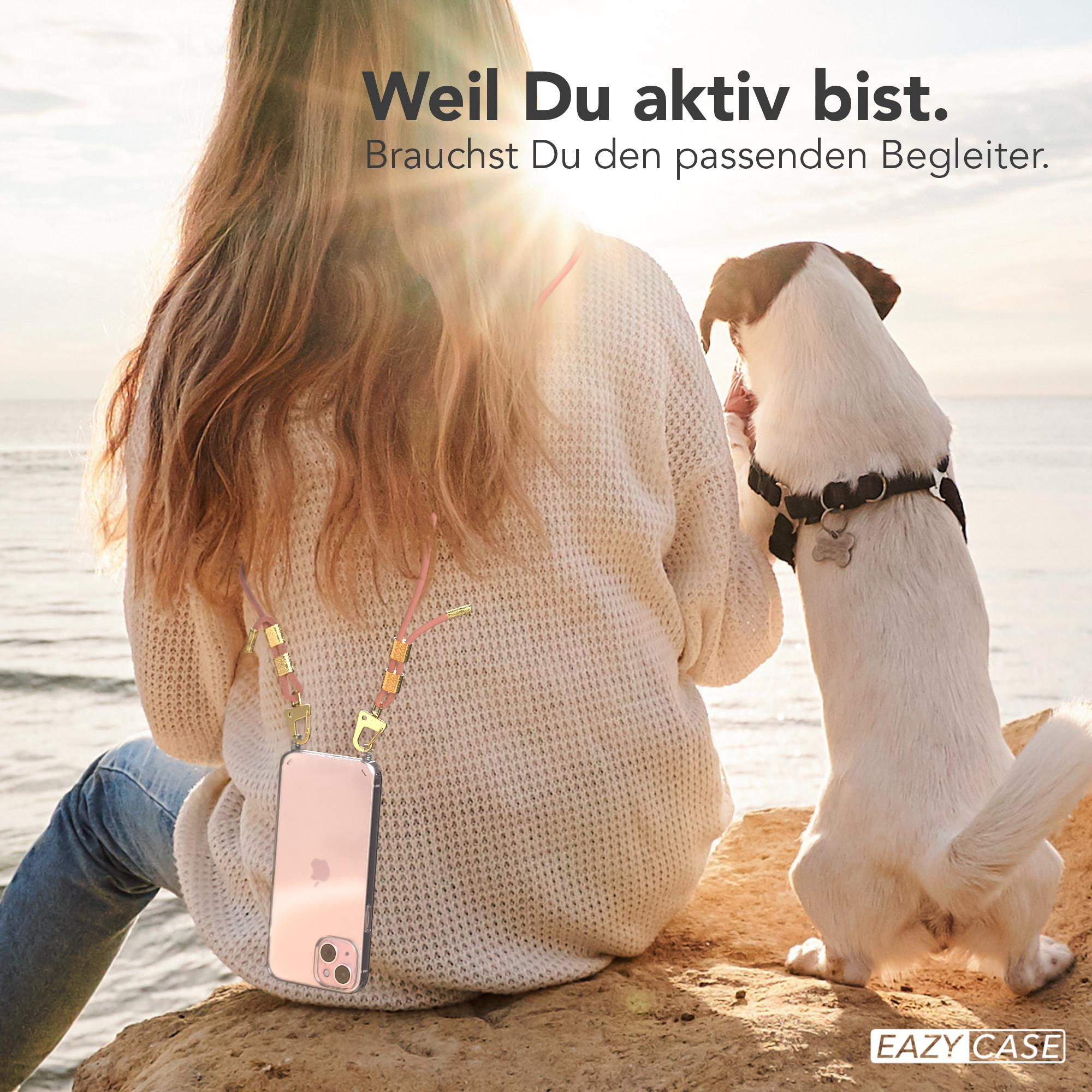 Frau mit Handyhülle und Hund am Meer. Die Frau trägt einen Pullover.