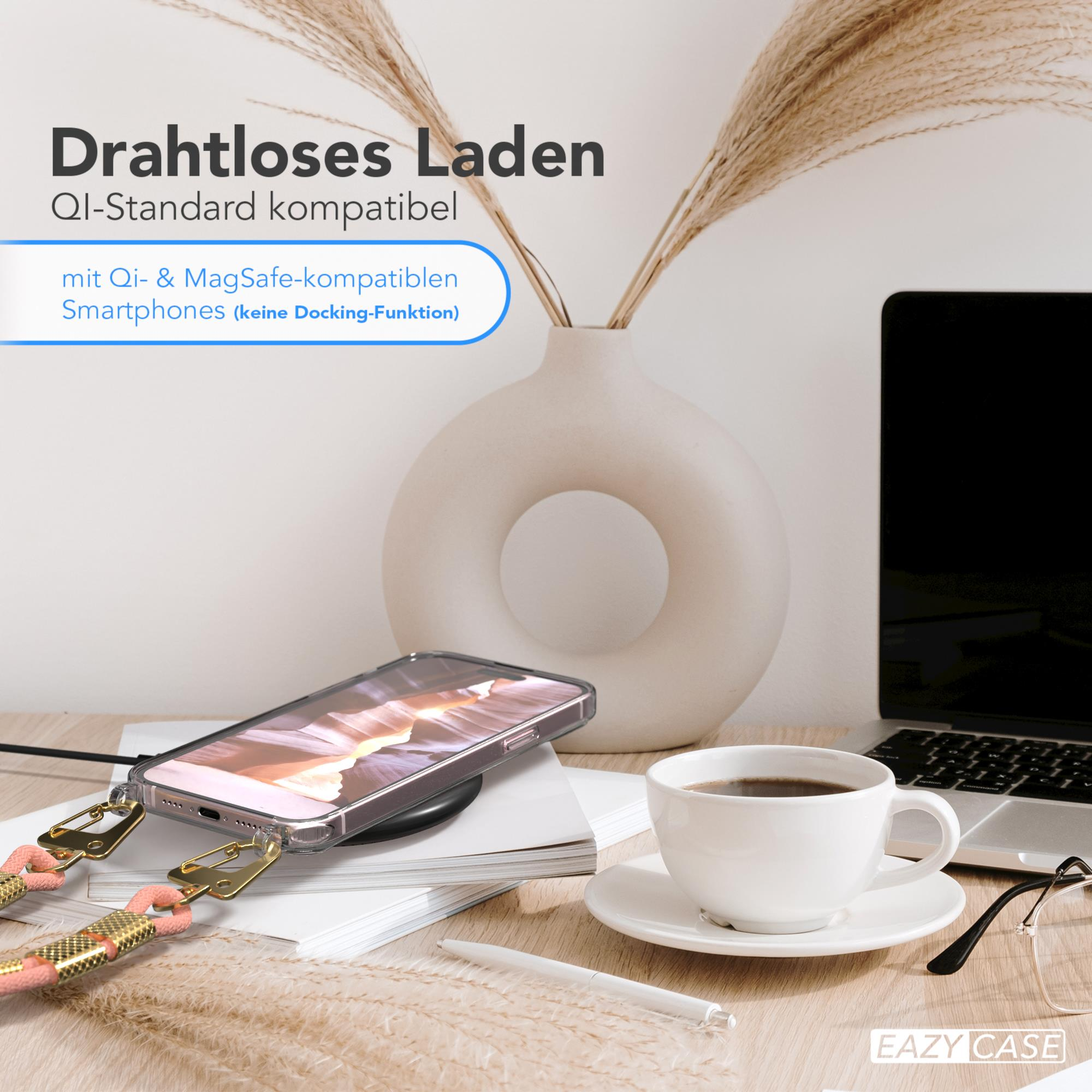 Telefon auf kabellosem Ladegerät, Kaffee und Laptop auf dem Schreibtisch. Vase mit Pflanzen im Hintergrund.
