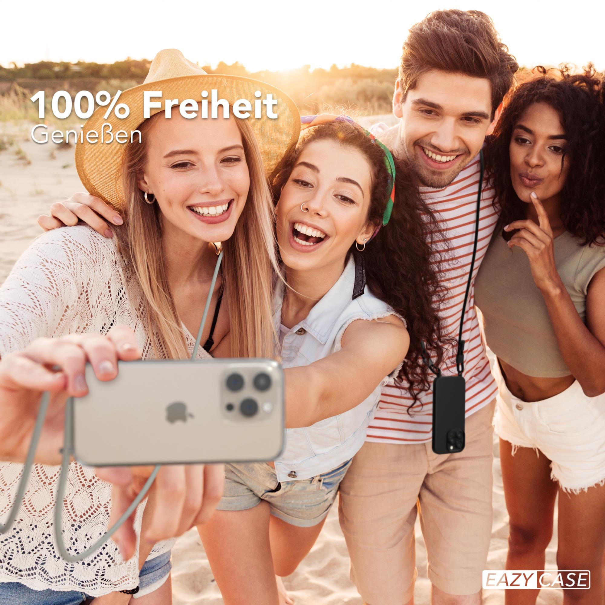 Vier Freunde machen ein Selfie am Strand und lächeln. Einer hält das Telefon mit einem Band.