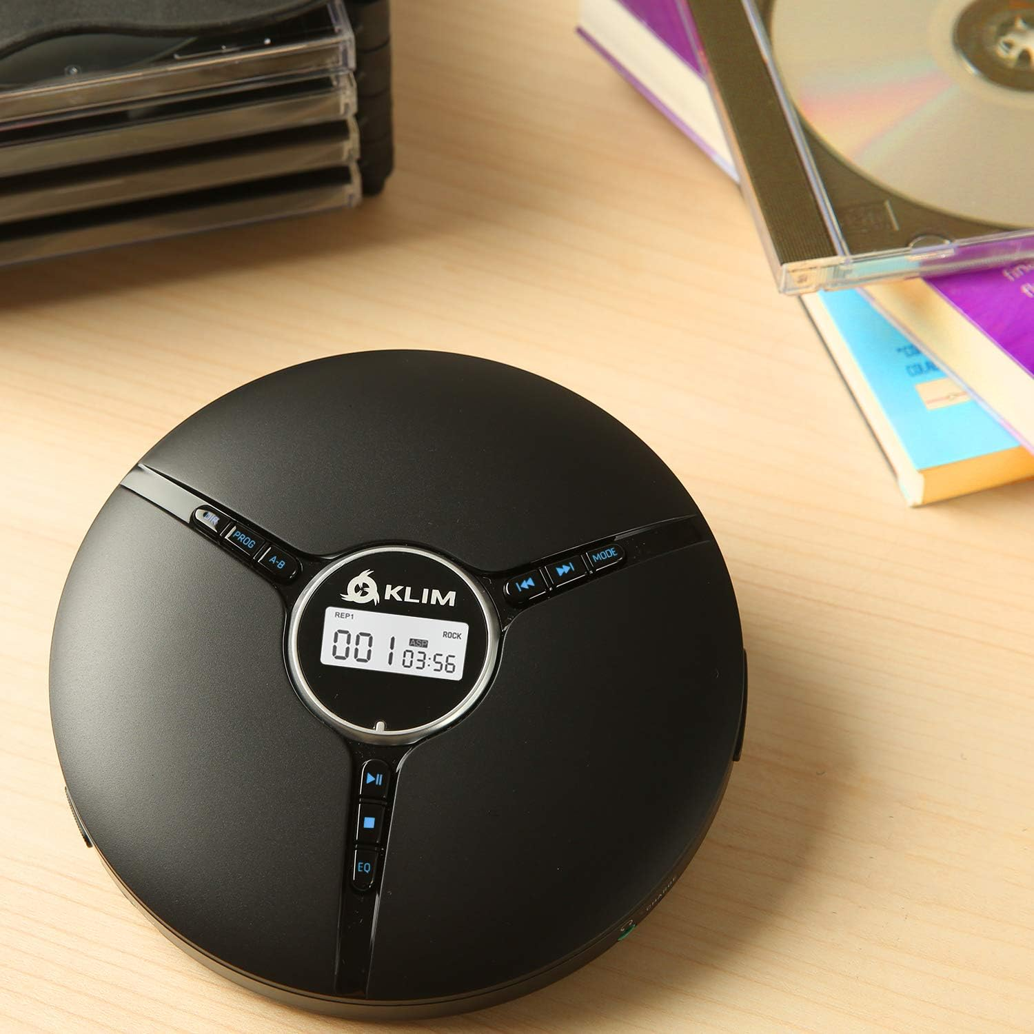 Ein schwarzer, runder CD-Player mit Display und CDs im Hintergrund.