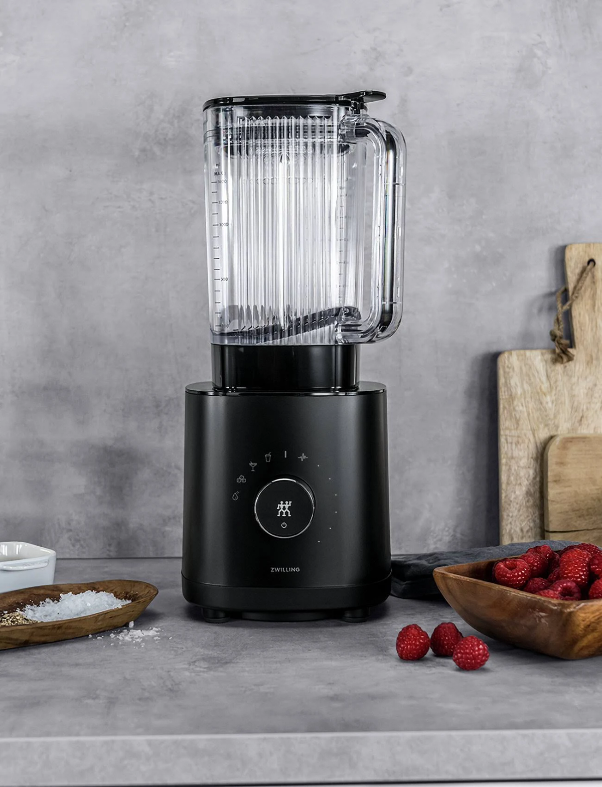 Schwarzer Mixer mit Glasbehälter. Himbeeren und Salz sind in der Szene.