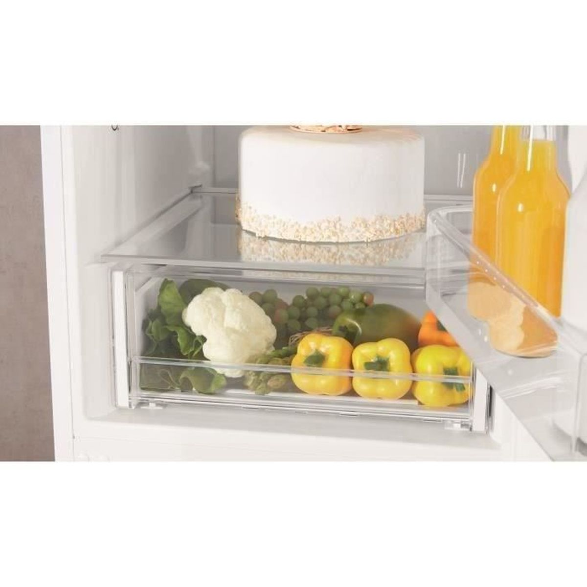 Dentro de un refrigerador, se ven verduras y un pastel en los estantes.