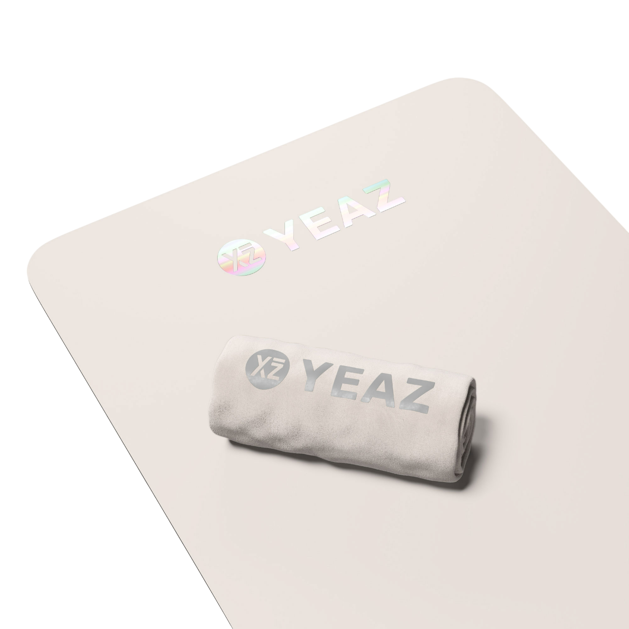 Eine weiße Matte mit einem gerollten Handtuch und dem Wort "YEAZ" in Silber, mit holografischem Logo.
