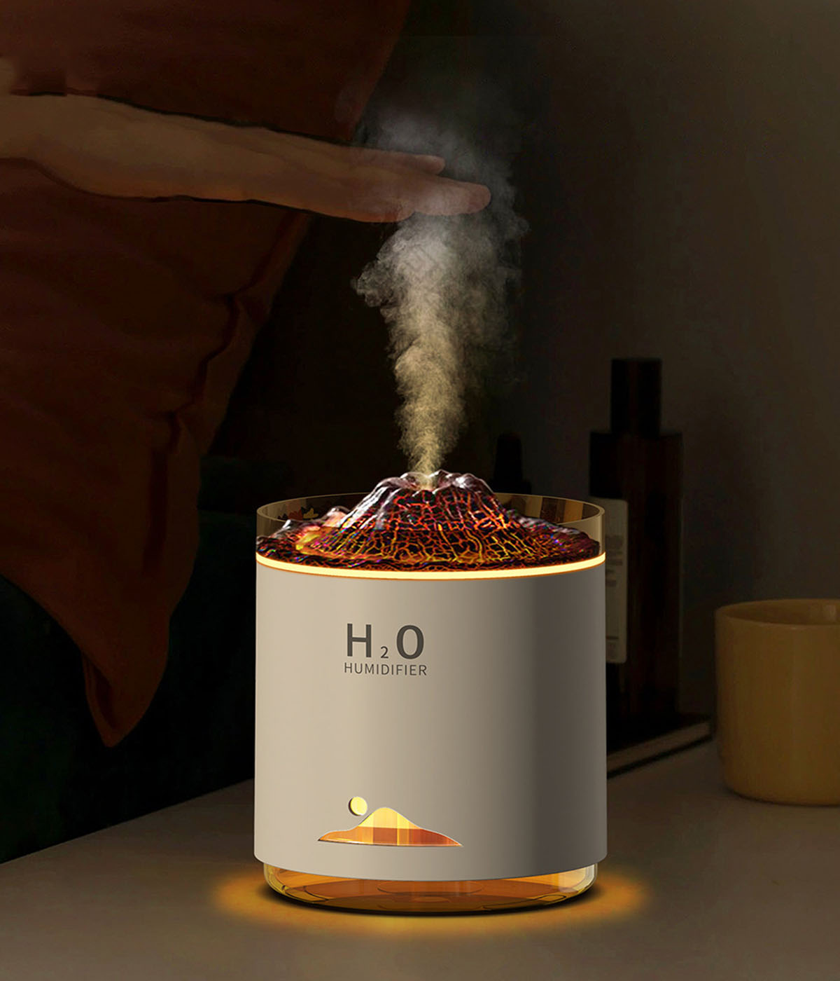 Ein weißer und orangefarbener Luftbefeuchter mit vulkanartigem Design, der Dampf abgibt.