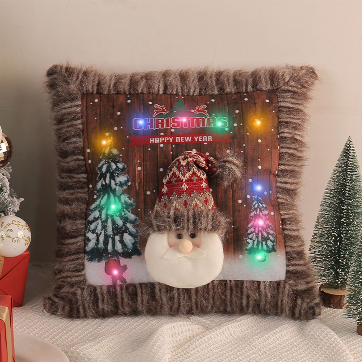 Weihnachtskissen mit Santa Claus, beleuchteten Weihnachtsbäumen und Schriftzug 'Christmas'.