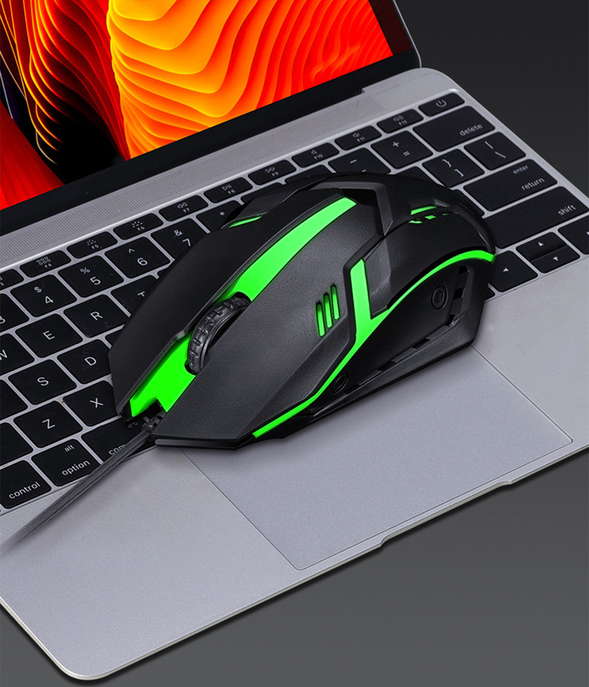 Eine schwarze Gaming-Maus mit grünen Akzenten liegt auf einer Laptop-Tastatur.