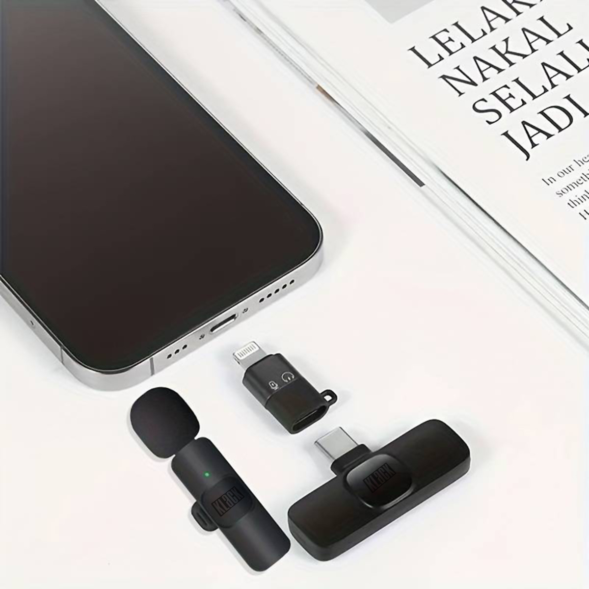 Smartphone negro con micrófono y adaptadores. Un papel y un smartphone en el fondo. Fondo blanco.