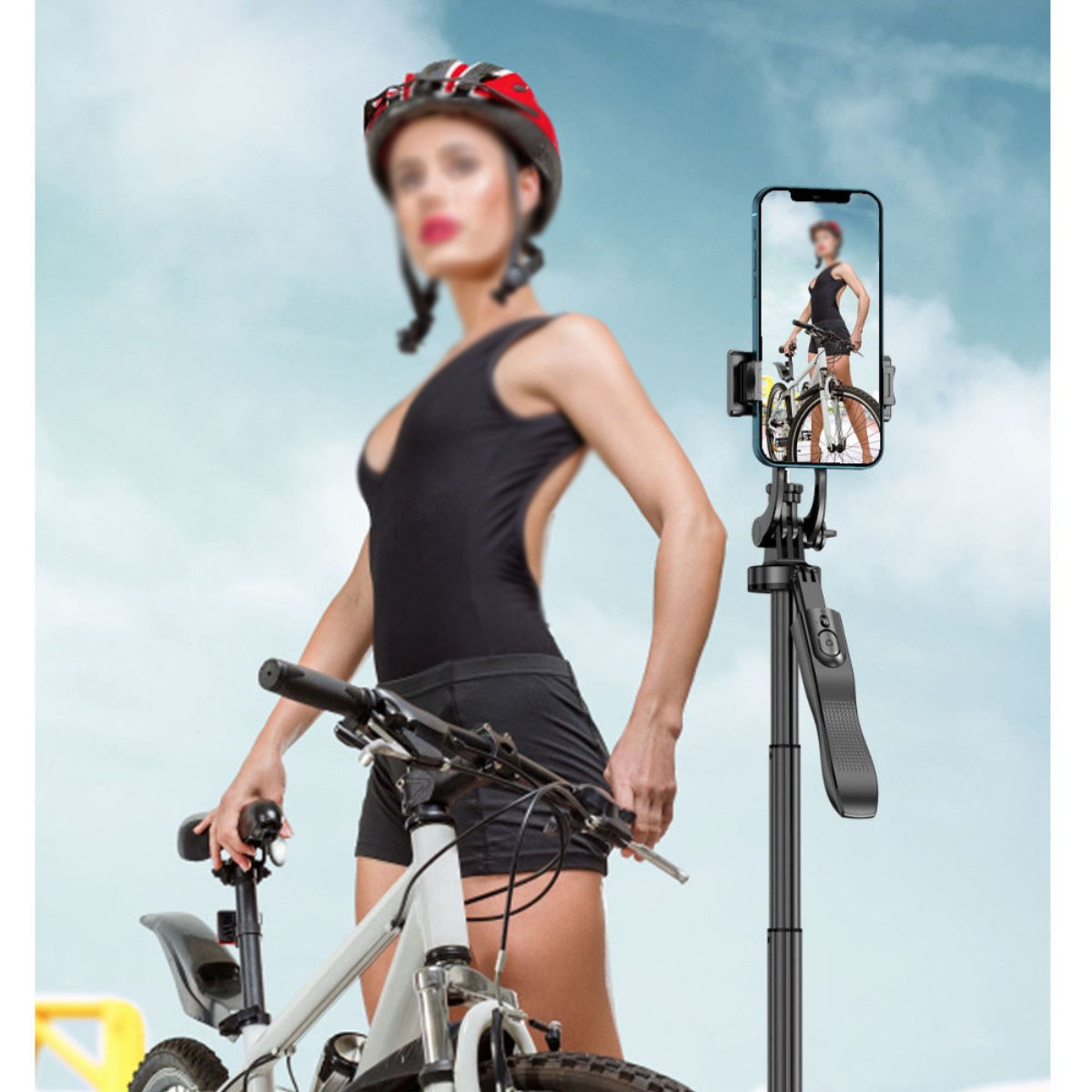Frau hält Fahrrad, Selfie-Stick mit Telefon zeigt Frau auf Fahrrad, blauer Himmel im Hintergrund.