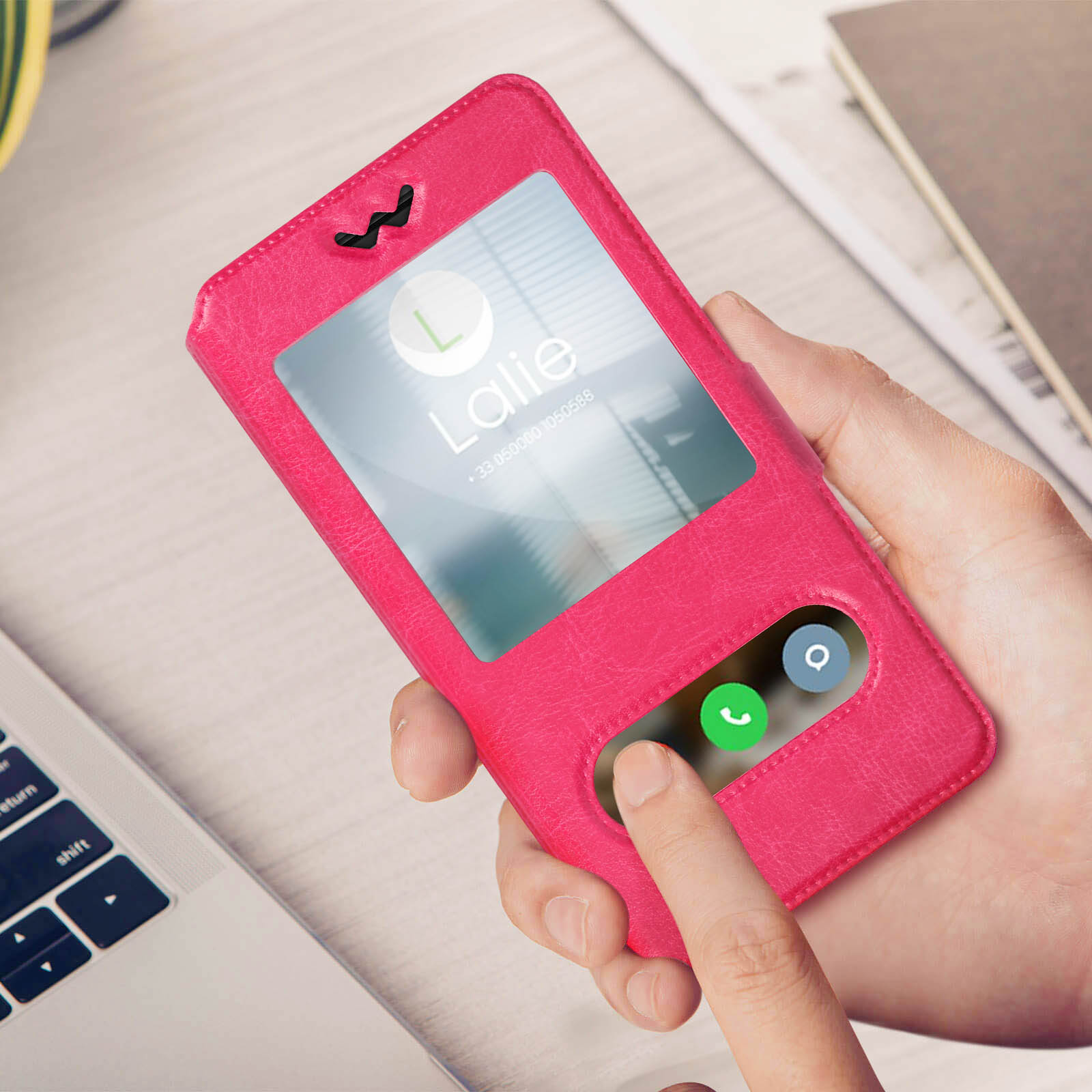 Una mano tiene una custodia rosa per telefono con un telefono che mostra una schermata di chiamata. Un dito tocca lo schermo.