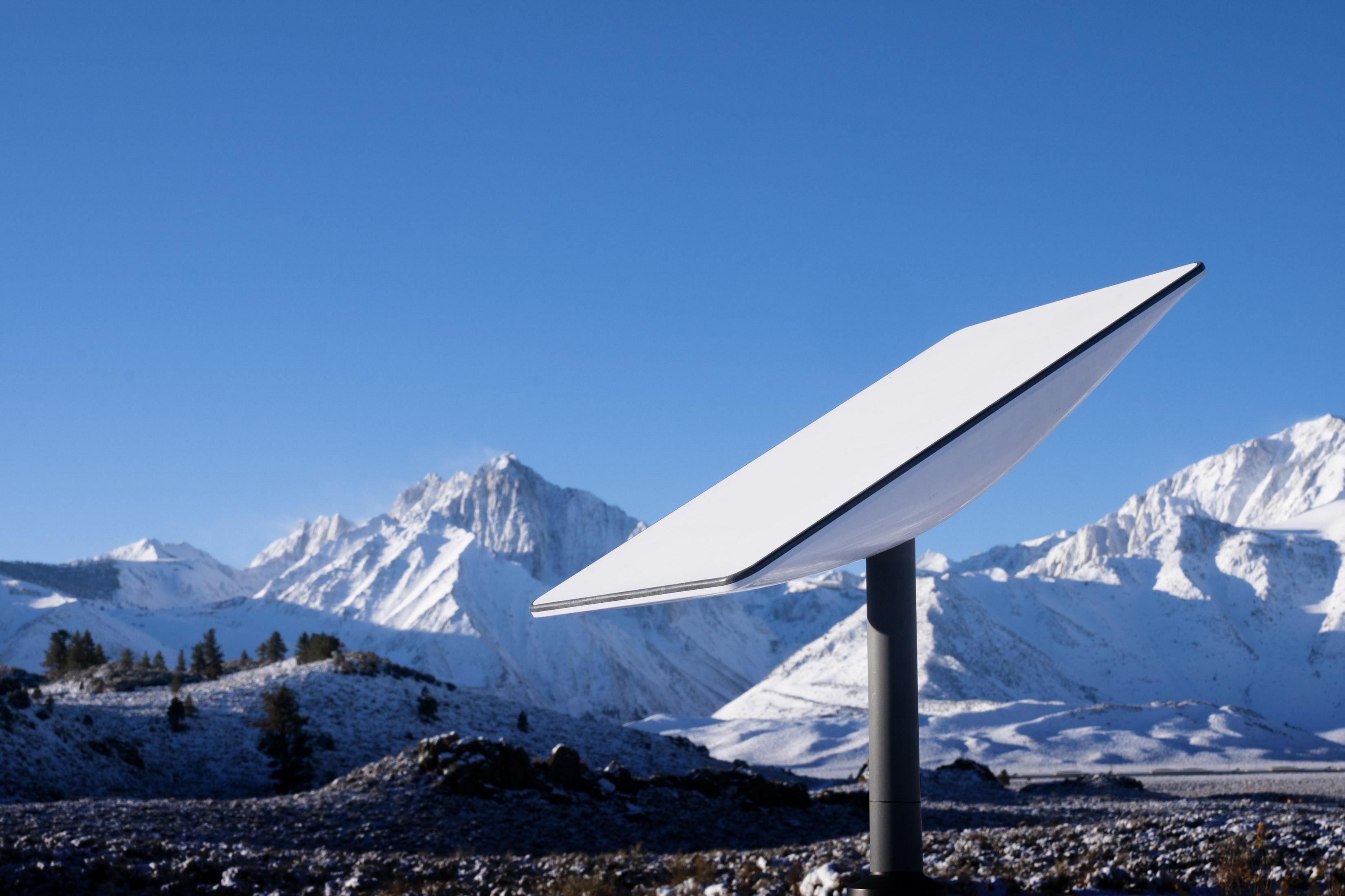 Eine Starlink-Schüssel vor schneebedeckten Bergen.
