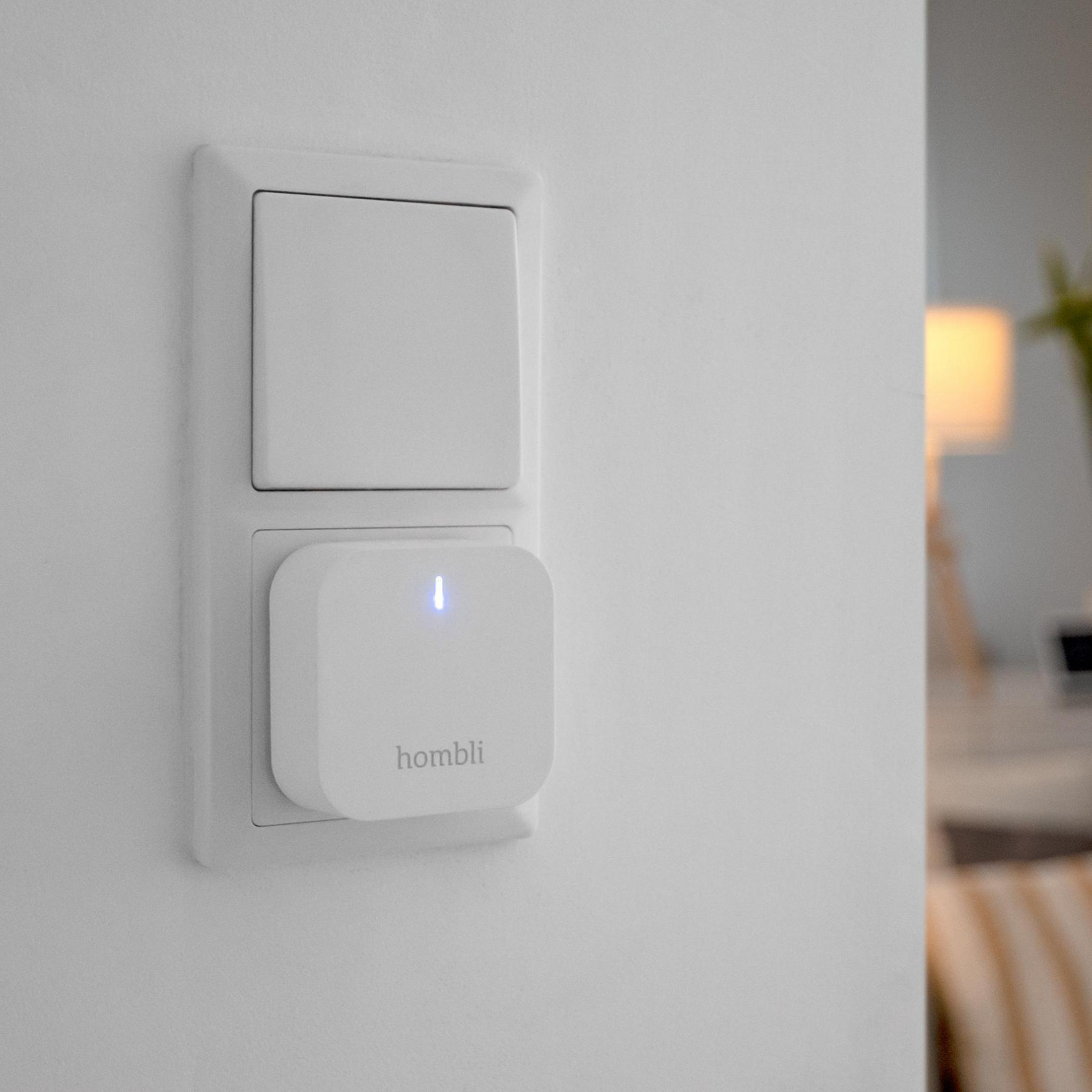 Weißer Lichtschalter mit einem installierten Smart-Stecker an der Wand.