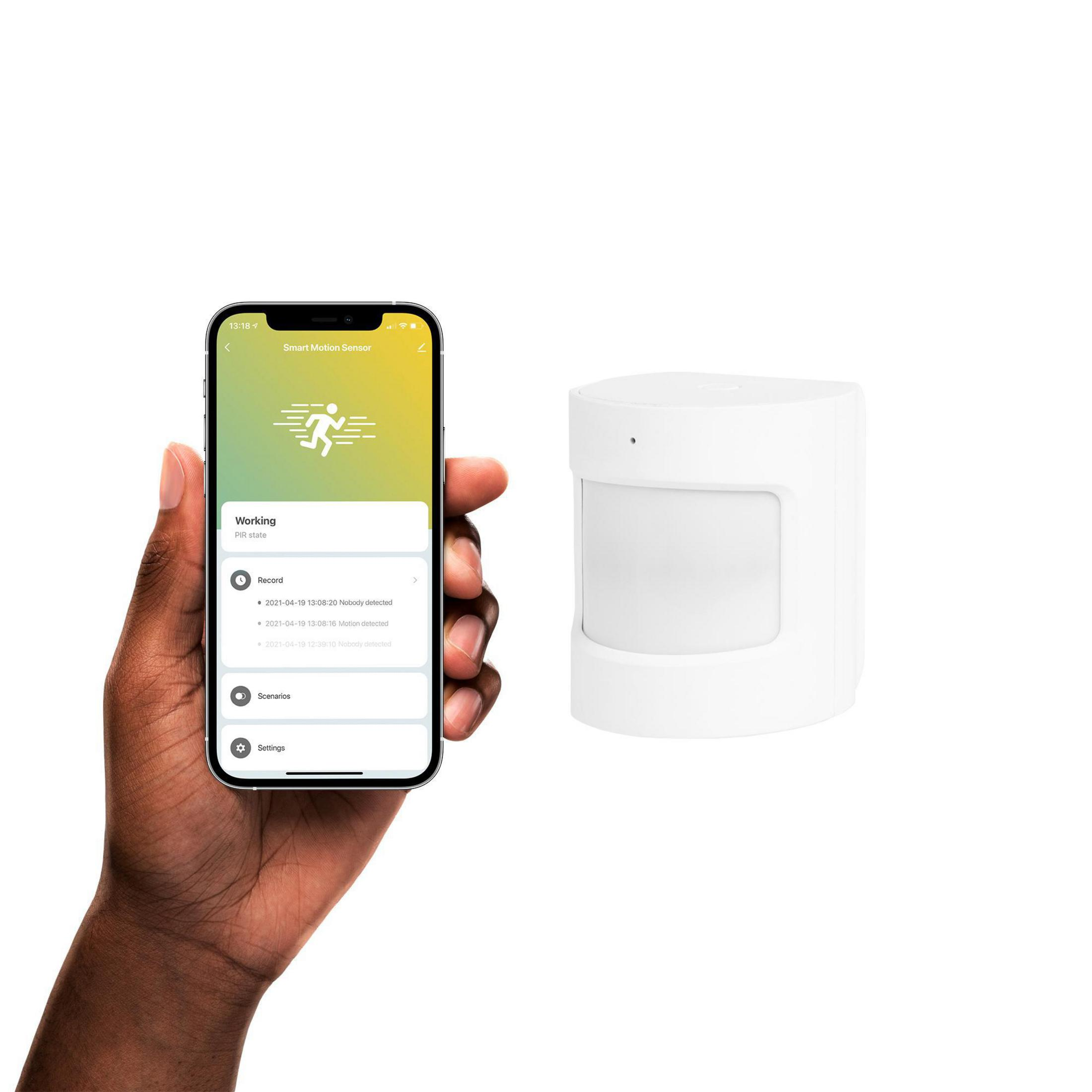 Una mano che tiene uno smartphone che mostra un'app per sensori di movimento intelligenti, accanto a un sensore bianco.