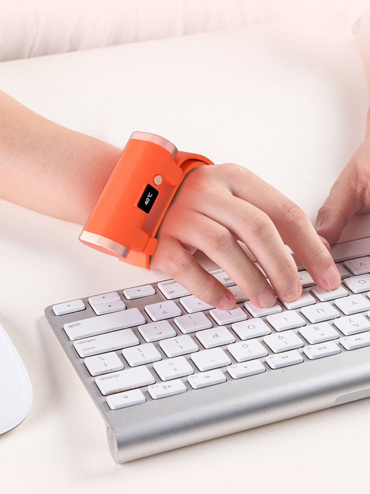 Person trägt oranges Armbandgerät mit Bildschirm, tippt auf Tastatur. Zeigt: 40°C.