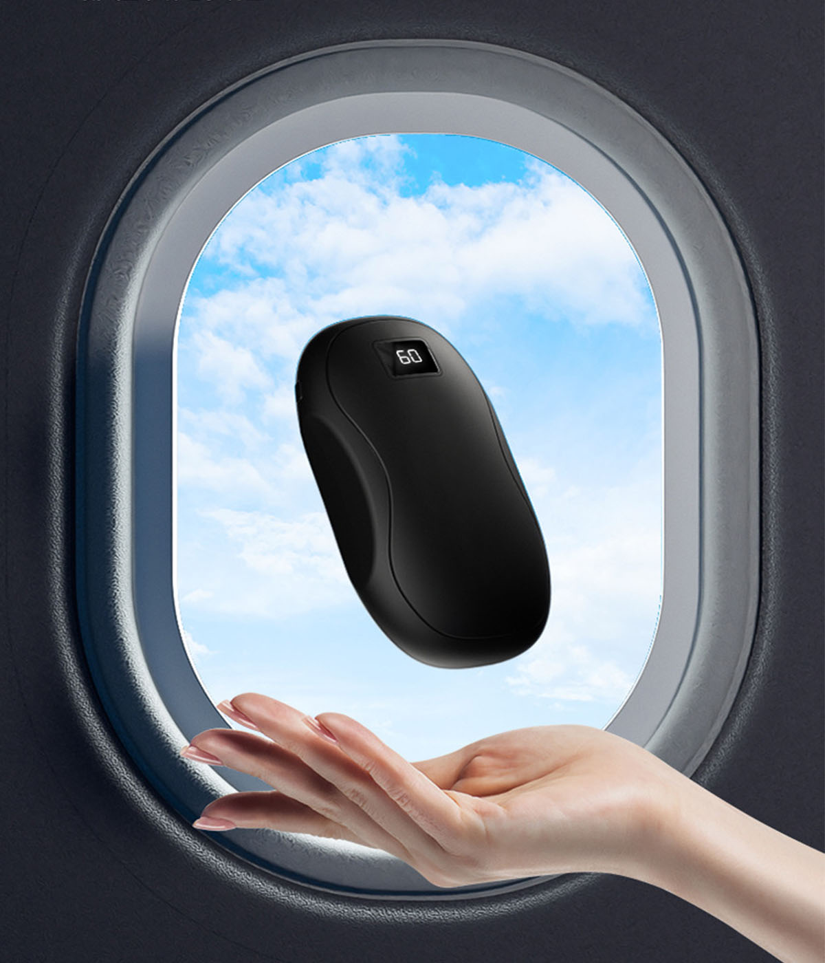 Hand hält ein schwarzes, ovales Gerät mit digitaler Anzeige. Der Hintergrund zeigt Himmel und ein Flugzeugfenster.
