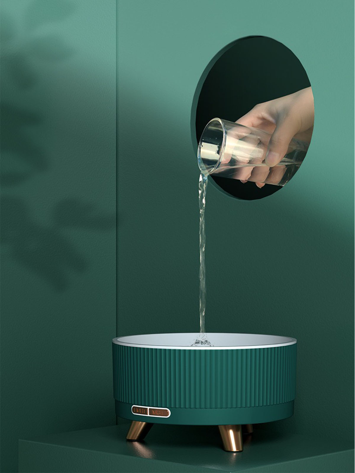 Hand gießt Wasser aus einem Glas in einen grünen und goldenen Haustierbrunnen.